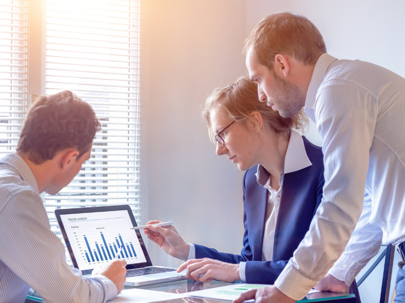 Group of accountants gathered around a laptop showing a chart - Accountancy based in Brentwood