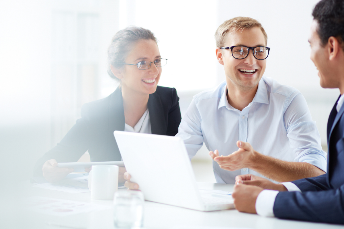 Group of businessmen and woman smile as they are sat around a laptop - Formation of the company